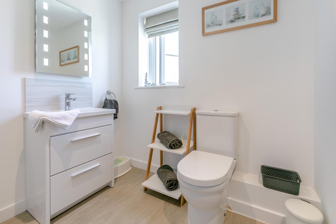 Une salle de bain moderne avec un meuble-lavabo blanc, des toilettes et une fenêtre.
