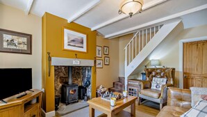 Una sala de estar acogedora con chimenea, televisor, una mesa de centro de madera y un sillón de cuero.