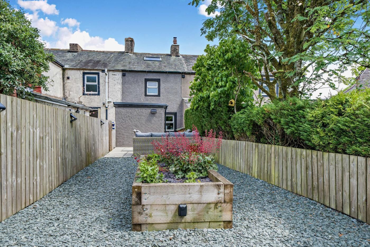 Il s'agit d'une propriété résidentielle dotée d'un chemin de gravier, d'une clôture en bois et d'un parterre agrémenté de plantes.