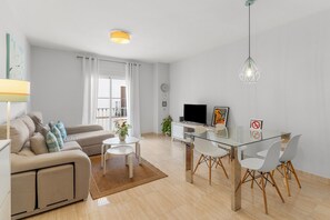 Ein modernes Wohnzimmer mit einer Couch, einem Glastisch und einem Fernseher.