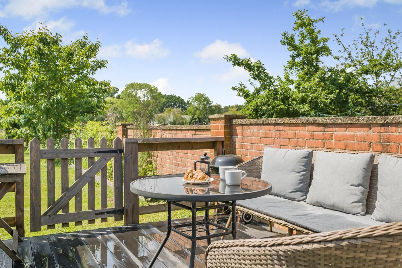 A patio with a glass table, a brick wall, and a wooden fence.