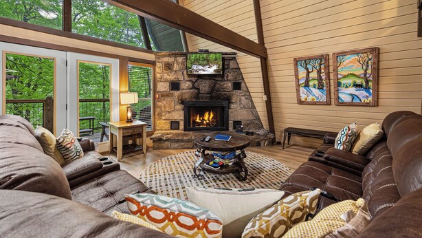 Una sala de estar acogedora con chimenea de piedra, asientos cómodos y grandes ventanales con vistas al exterior.