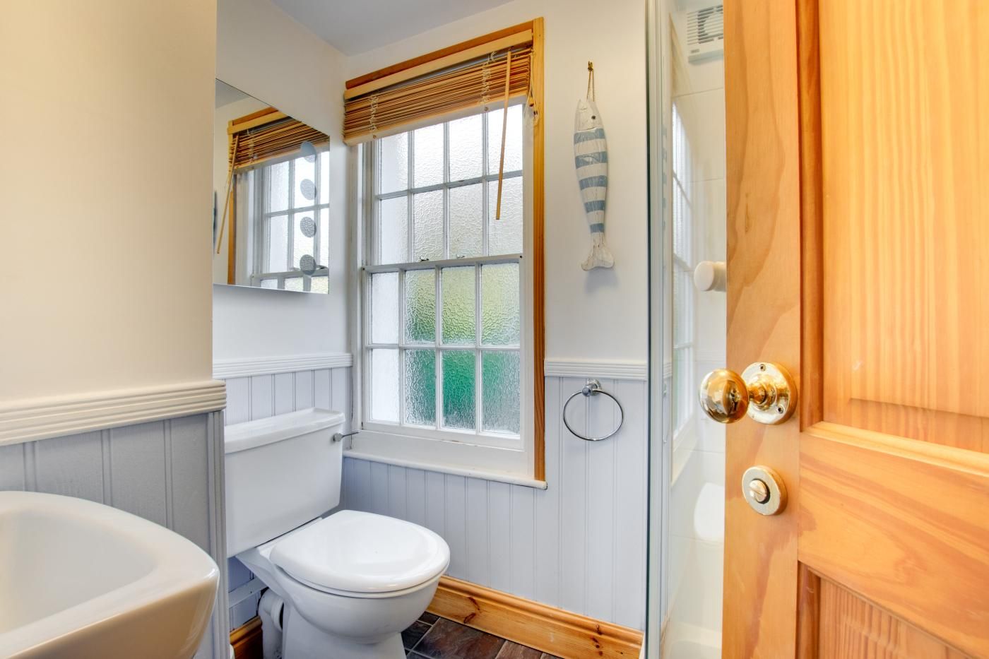 A bathroom with a toilet, a bathtub, and a window with blinds.