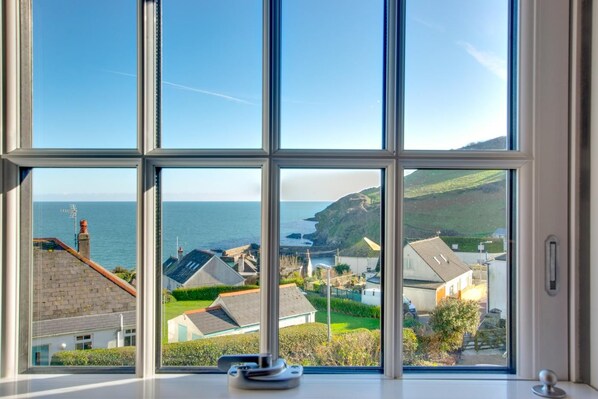 Una ventana con vistas a un pueblo costero, casas y el mar.