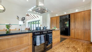 Une cuisine moderne avec des meubles en bois, une cuisinière noire et un pare-feu en verre.