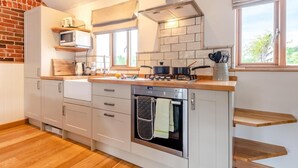 A compact kitchen with white cabinets, a built-in oven, a microwave, and a gas stove. - 1 Bed in Blashford (oc-d32251) (Ringwood)