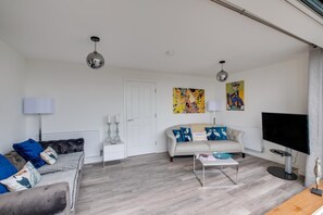 Een woonkamer met een bank, een salontafel, een televisie en kunst aan de muur.