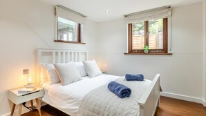 Ein Schlafzimmer mit einem Bett, einem Nachttisch und zwei Fenstern.