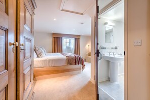 A bedroom with a bed, a bedside table, and a view into a bathroom with a sink and mirror. - 5 Bed in Battle (oc-l32238) (Battle)