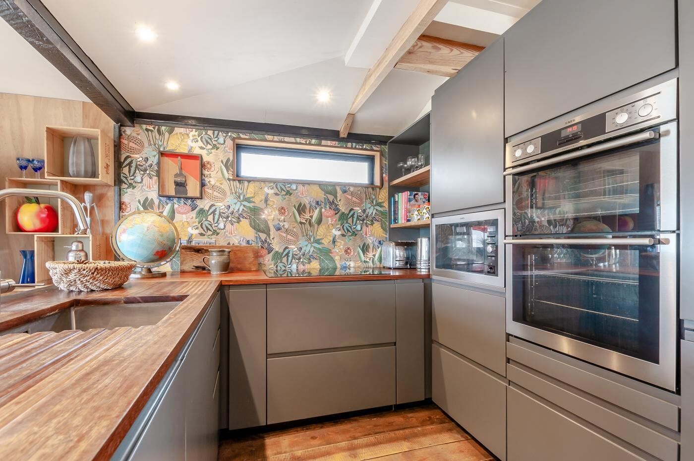 Une cuisine moderne avec un plan de travail en bois, des meubles de couleur grise et un four double.