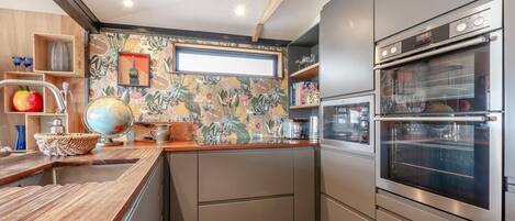 Une cuisine moderne avec un plan de travail en bois, des meubles de couleur grise et un four double.