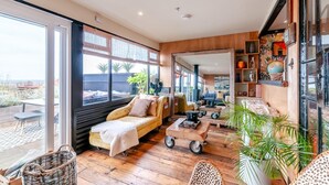 A spacious living area with a large window, a sofa, a coffee table, and a bookshelf.