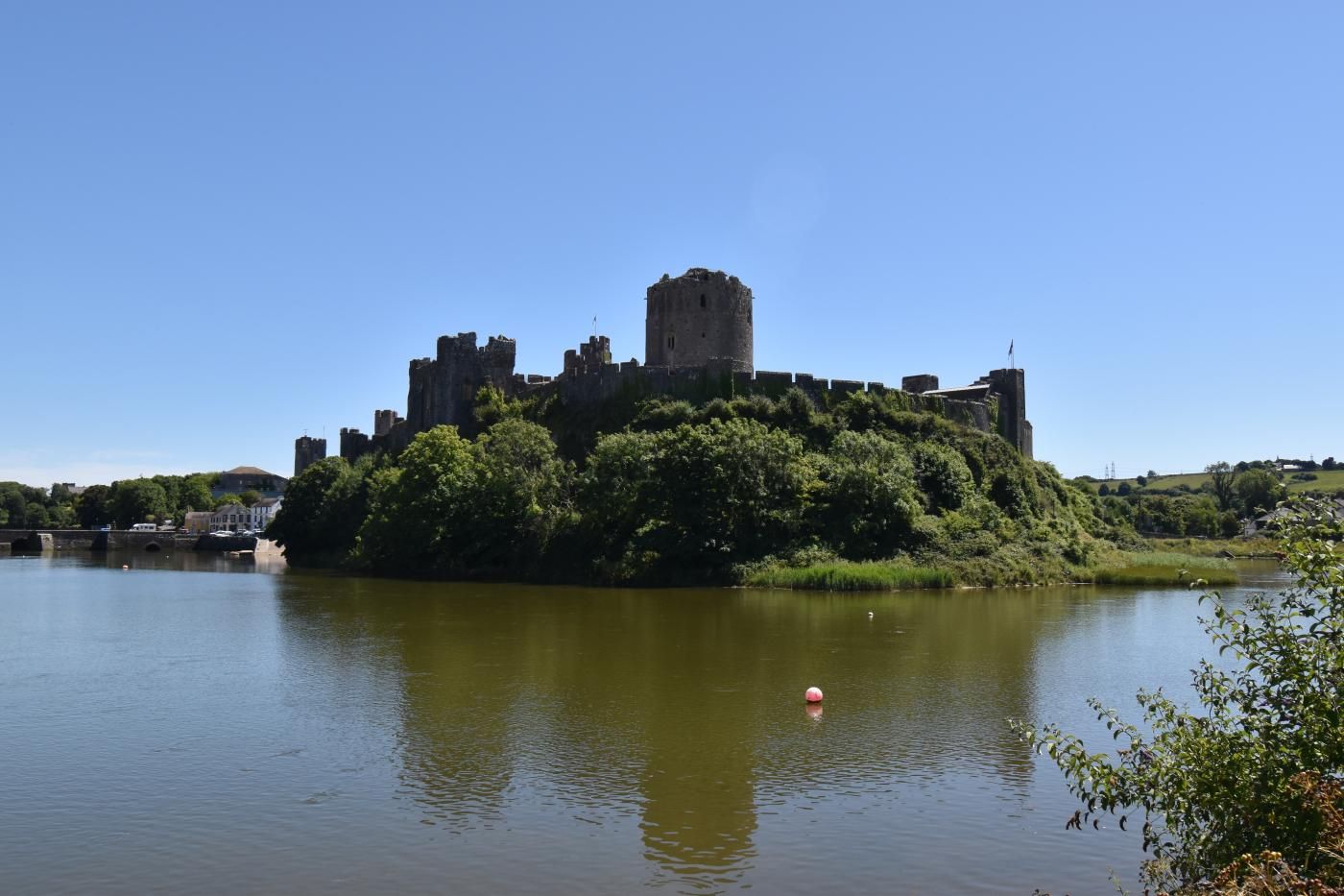 Un castello storico su una collina che domina un fiume tranquillo.