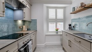 A modern kitchen with a window, a built-in oven, and a sink. - 2 Bed in Tenby (oc-c32240) (Tenby)