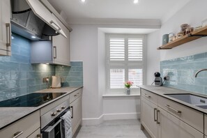 A modern kitchen with a window, a built-in oven, and a sink. - 2 Bed in Tenby (oc-c32240) (Tenby)