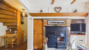 A cozy living room with a fireplace, wooden beams, a stone fireplace surround, and a television. - 2 Bed in Whitby (oc-w014) (Whitby)