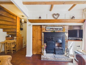 A cozy living room with a fireplace, wooden beams, a stone fireplace surround, and a television. - 2 Bed in Whitby (oc-w014) (Whitby)