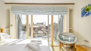 Habitación de hotel con una cama grande, una silla, vistas de la ciudad y un balcón.