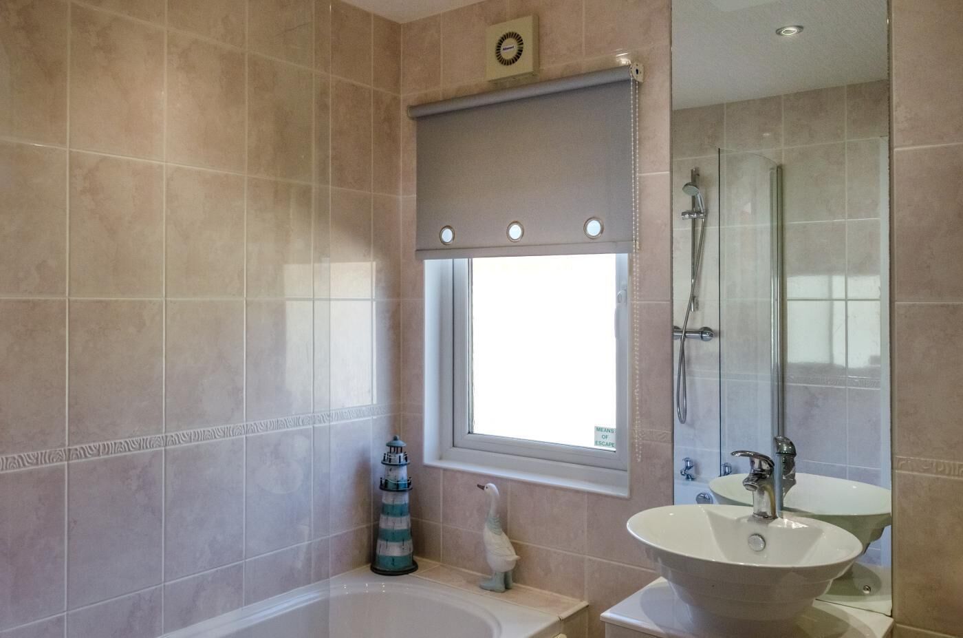 A bathroom with a bathtub, a sink, a window, and a shower.