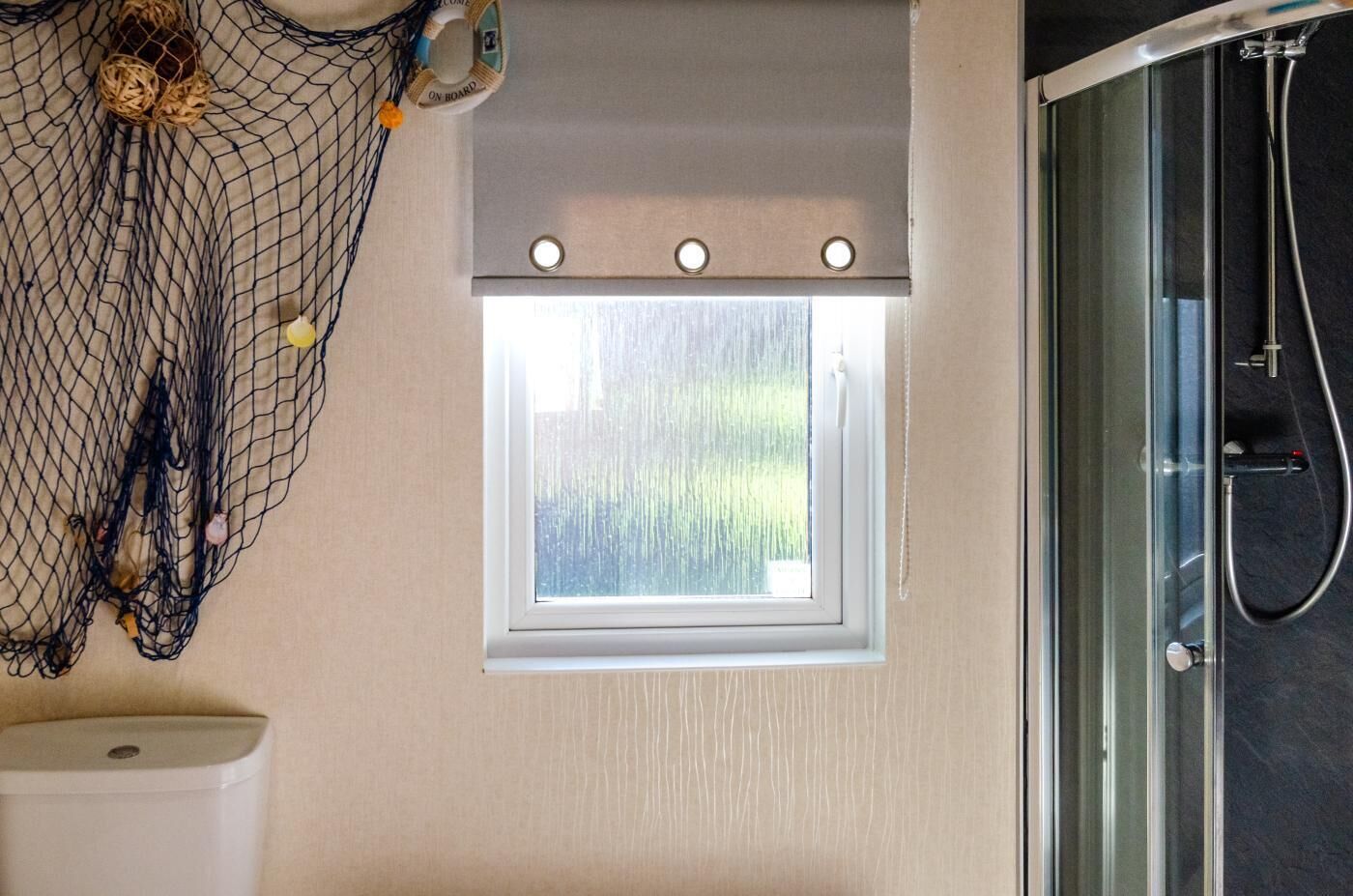 A bathroom with a small window, a shower, and a toilet.