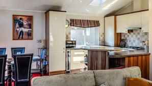 Una cocina moderna con una isla central, un comedor con sillas y una sala de estar con sofá.