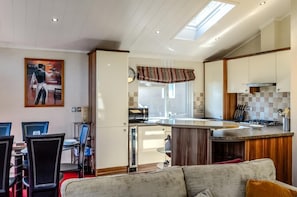 A modern kitchen with a central island, a dining area with chairs, and a living room with a sofa. - 2 Bed in Stepaside (oc-pw9184) (Stepaside)