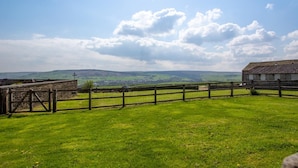 A grassy field with a stone wall and wooden fence, overlooking rolling hills and a clear sky. - 1 Bed in Cowling (oc-ds237) (Cowling)