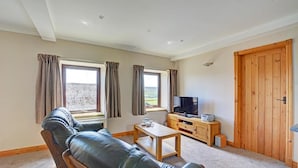 A living room with a leather sofa, a TV, and a wooden cabinet. - 1 Bed in Cowling (oc-ds237) (Cowling)