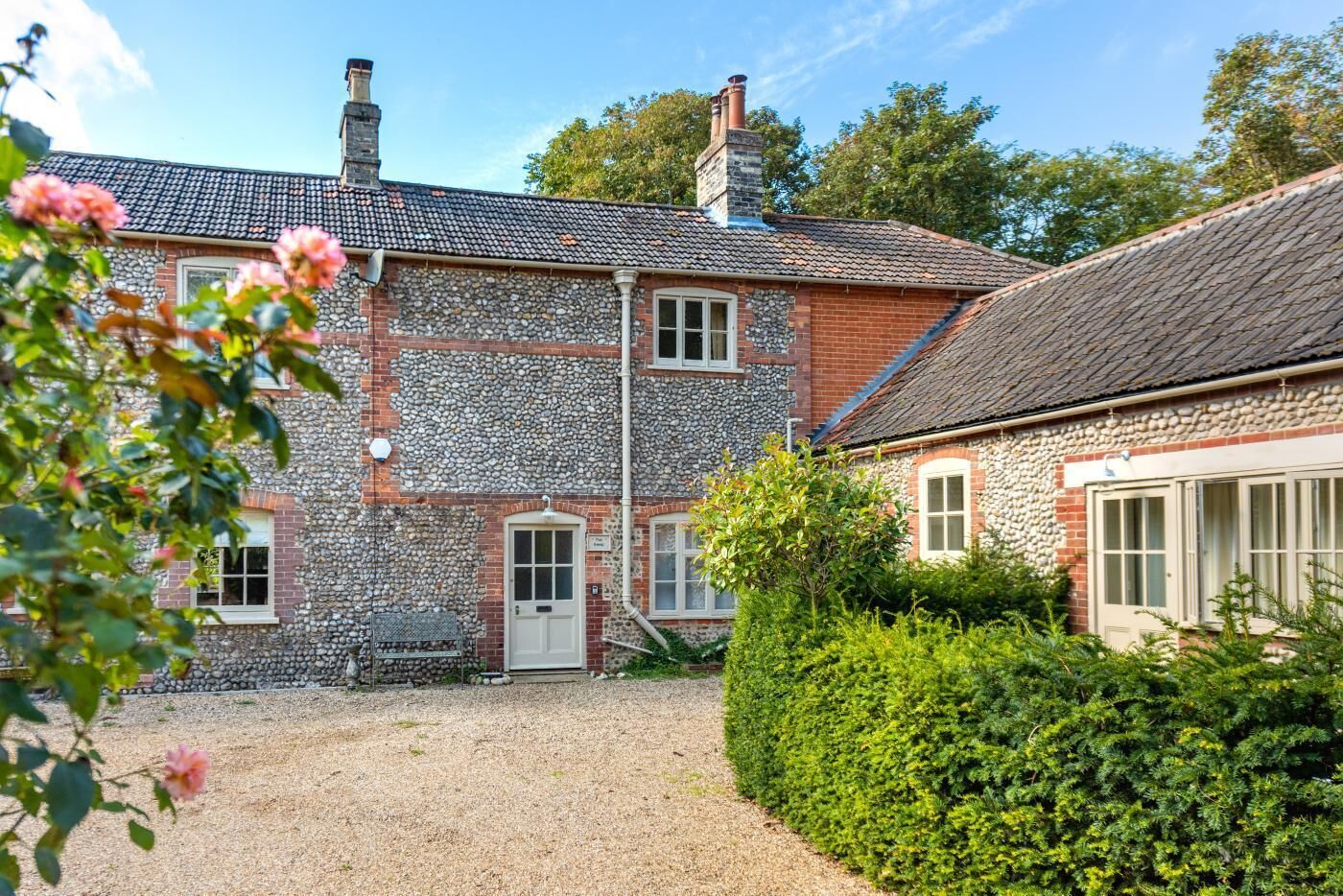 A stone house with a gravel driveway and a well-maintained hedge.