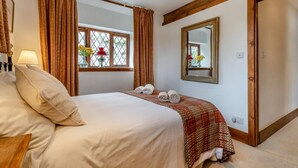 Quarto de hotel com cama, janela com cortinas, espelho e mesa de cabeceira com abajur.
