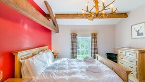 Un dormitorio con una cama de madera, un candelabro, una ventana con cortinas y un aparador.