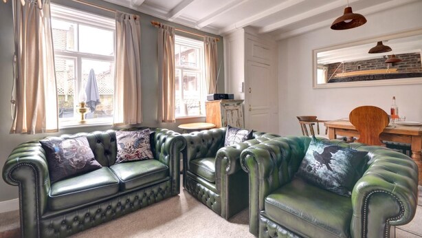 A living room with a green leather sofa set, a dining table with chairs, and a hanging pendant light. - 2 Bed in Whitby (oc-w353a) (Whitby)