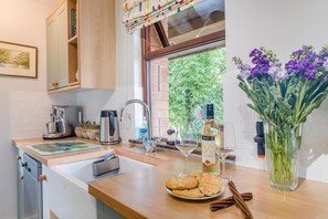 A modern kitchen with a wooden countertop, stainless steel appliances, and a window with a view of greenery. - 2 Bed in Bassaleg (oc-d32378) (Bassaleg)