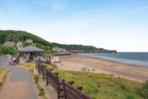 A coastal road with a beach, benches, and a small pavilion. - 3 Bed in Sandsend (oc-wa081) (Sandsend)