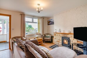 A cozy living room with a sofa, a chair, a fireplace, and a television. - 3 Bed in Sandsend (oc-wa081) (Sandsend)