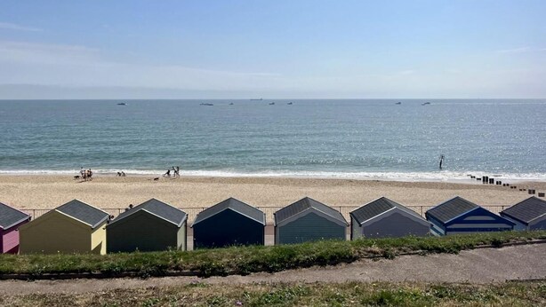 A beach with a row of colorful beach huts in the foreground and a clear blue sky. - 3 Bed in Corton (oc-s32347) (Corton)