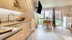 A modern kitchen with a built-in oven, a dining area with a table and chairs, and a large window offering a view of the outside. - 3 Bed in Corton (oc-s32347) (Corton)