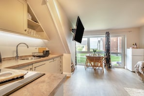 Una cocina moderna con horno empotrado, una zona de comedor con mesa y sillas, y un ventanal con vistas al exterior.