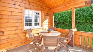 A wooden deck with a table and chairs, a window, and a hedge in the background. - 1 Bed in Pickering (oc-y290) (Middleton)