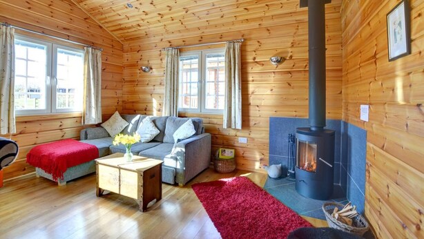 A cozy cabin interior with a sofa, a coffee table, a fireplace, and a large window. - 1 Bed in Pickering (oc-y290) (Middleton)