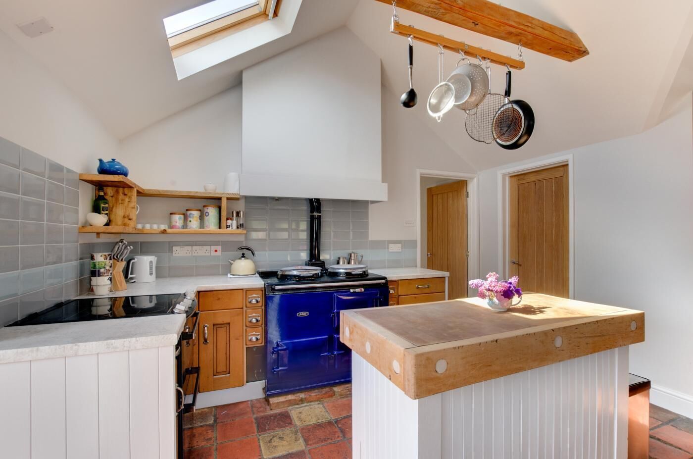 A modern kitchen with a blue stove, wooden cabinets, and a wooden countertop.