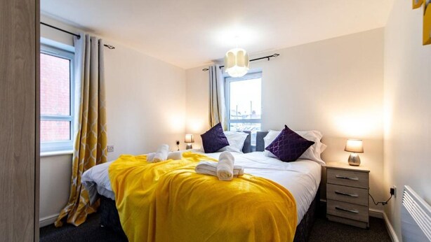 A hotel room with a bed, two bedside tables, a window, and a radiator. - Apartment - Sleeps 2 - Parking - City Centre Close (Coventry)