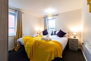 Ein Hotelzimmer mit einem Bett, zwei Nachttischen, einem Fenster und einer Heizung.