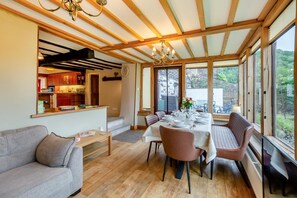 Un espace repas doté d’un plafond en bois, de grandes fenêtres et d’une vue sur l’extérieur.