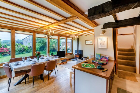 A dining area with a table set for four, a television, and a fireplace. - 4 Bed in Satterthwaite (oc-c32334) (Satterthwaite)