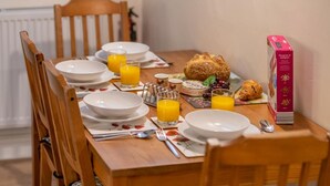 Uma mesa de jantar posta com pratos, talheres e itens de café da manhã, incluindo croissants e suco.