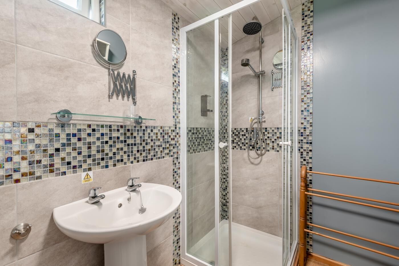 A bathroom with a sink, mirror, shower, and glass door.