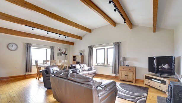 Ein geräumiges Wohnzimmer mit einer großen Couch, einem Esstisch mit Stühlen, einem Fernseher und einem Kamin.