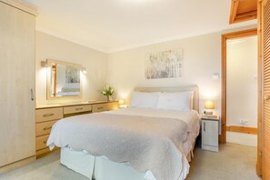 Une chambre à coucher avec un lit, des tables de chevet, une commode, un miroir et un tableau accroché au mur.