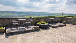 Eine Terrasse im Freien mit Blick auf sanfte Hügel und einen klaren Himmel.